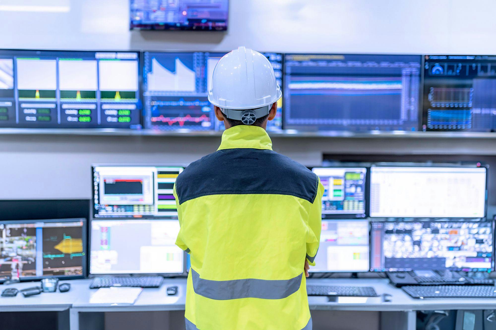 Engineer managing control systems with TAG in a high-tech control room with multiple monitors.